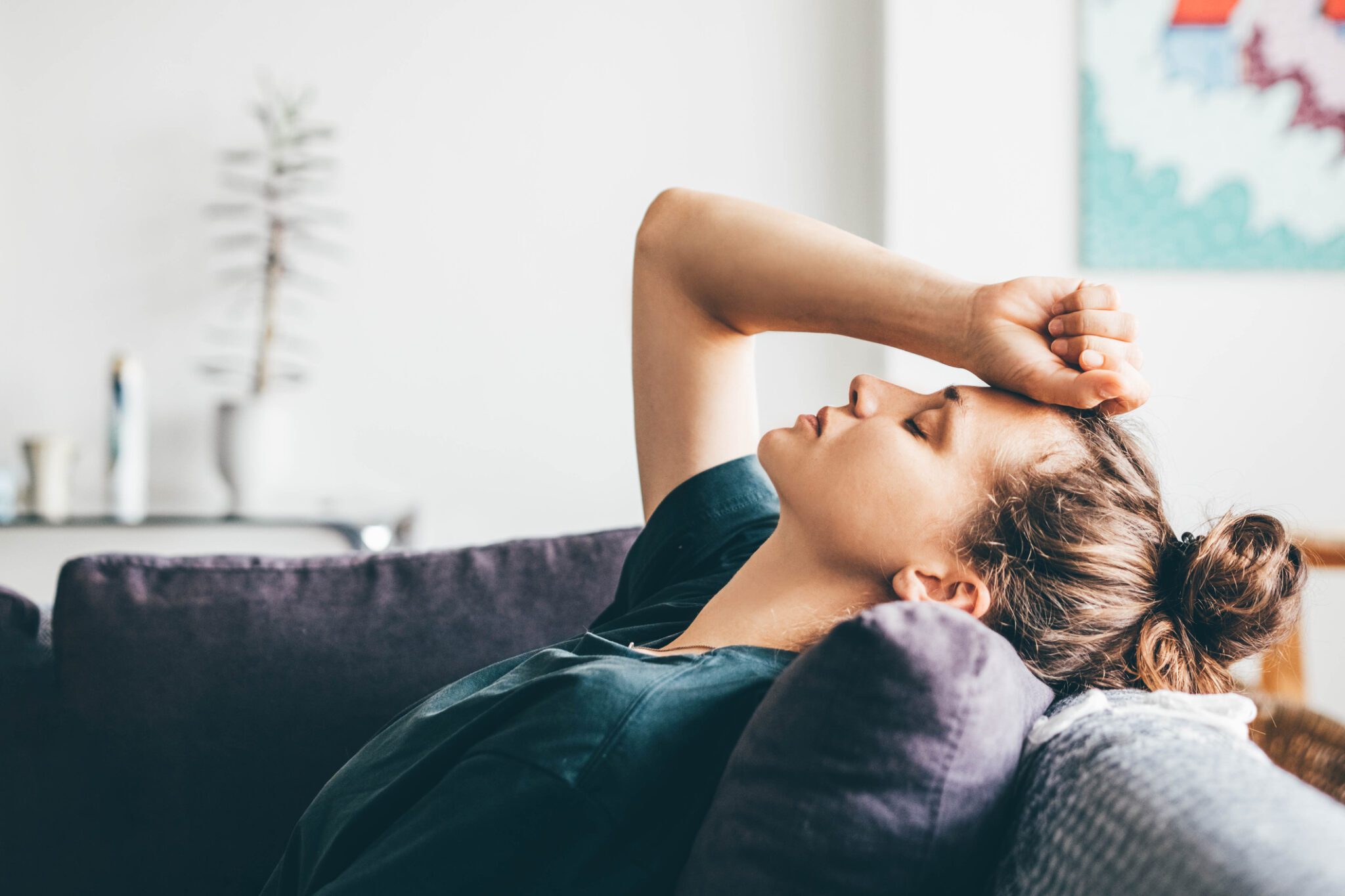 A woman rests on a couch, her head in her hands, conveying a sense of contemplation or distress.