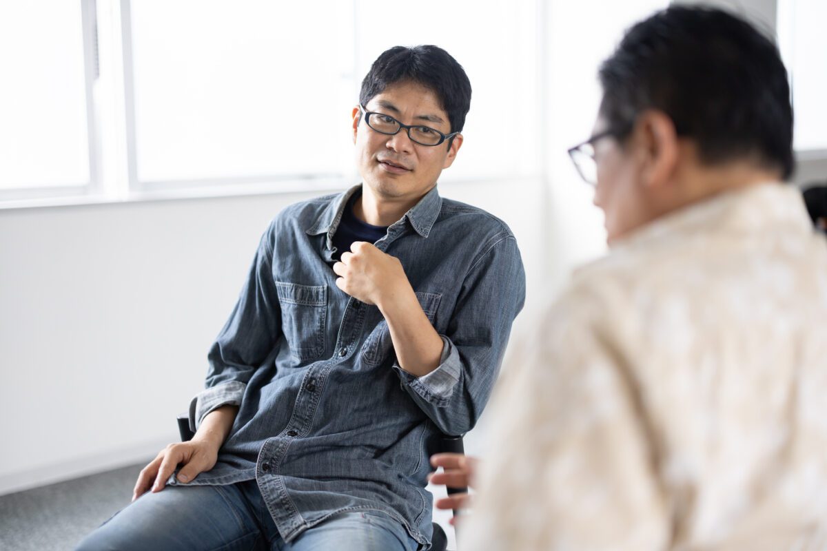 Asian man listens to a peer in group therapy discuss his problems