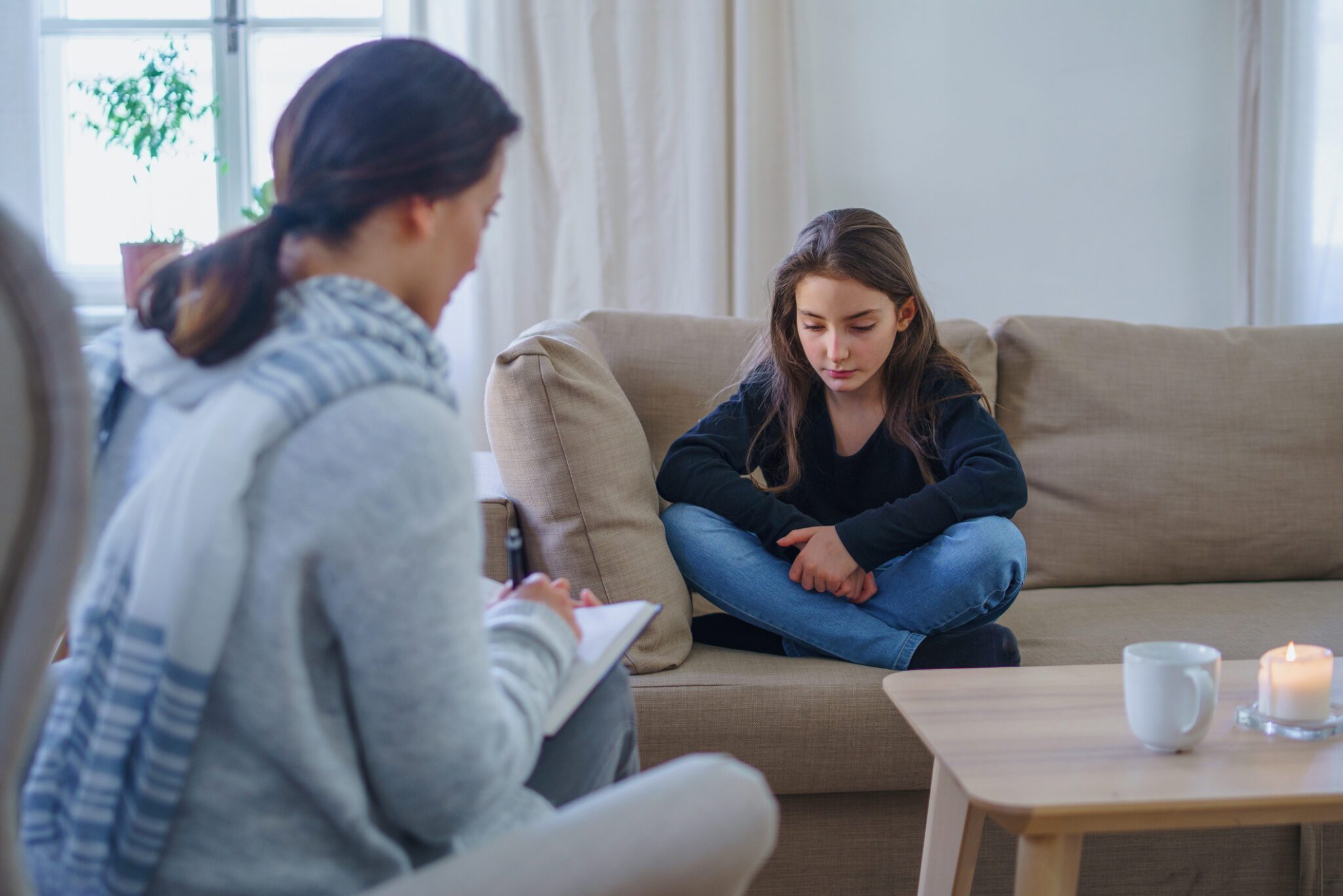 A woman and a child sit together on a couch, sharing a moment of comfort and companionship.